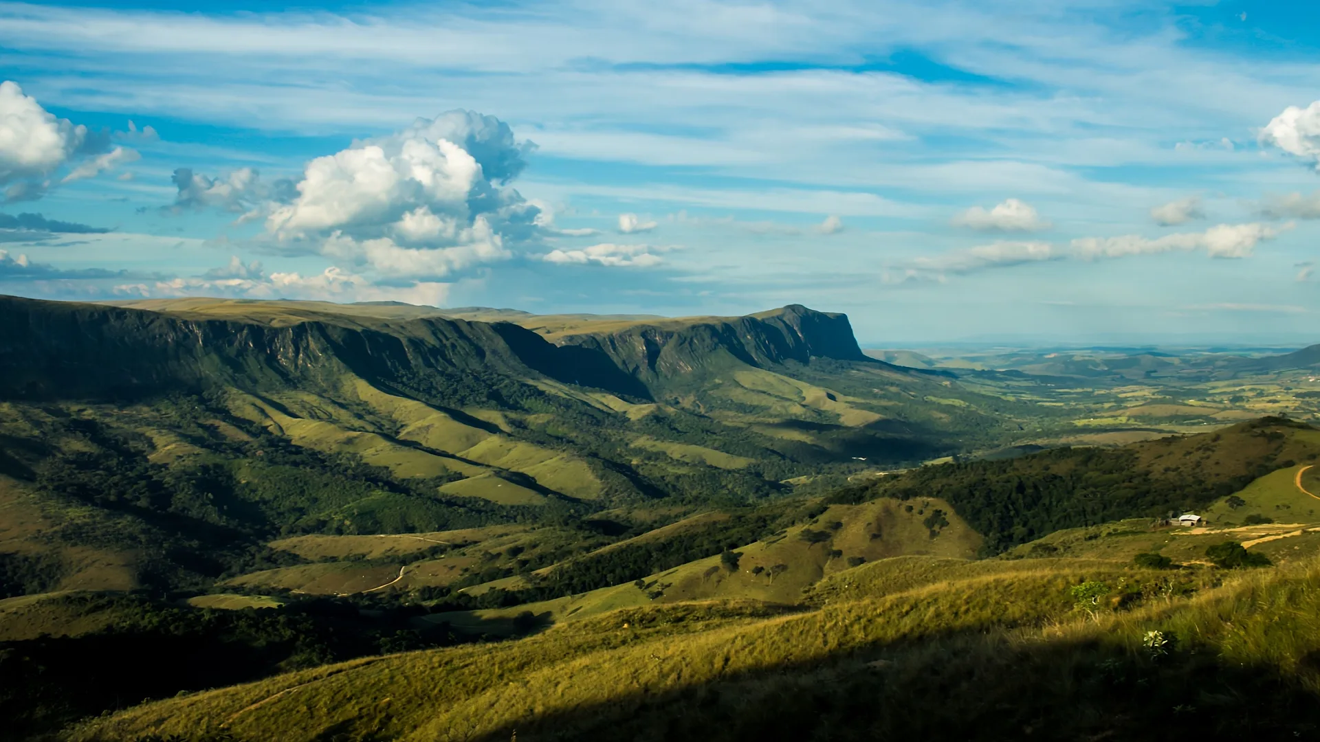 Escarpas e vales verdes da Serra da Canastra sob um céu azul com nuvens